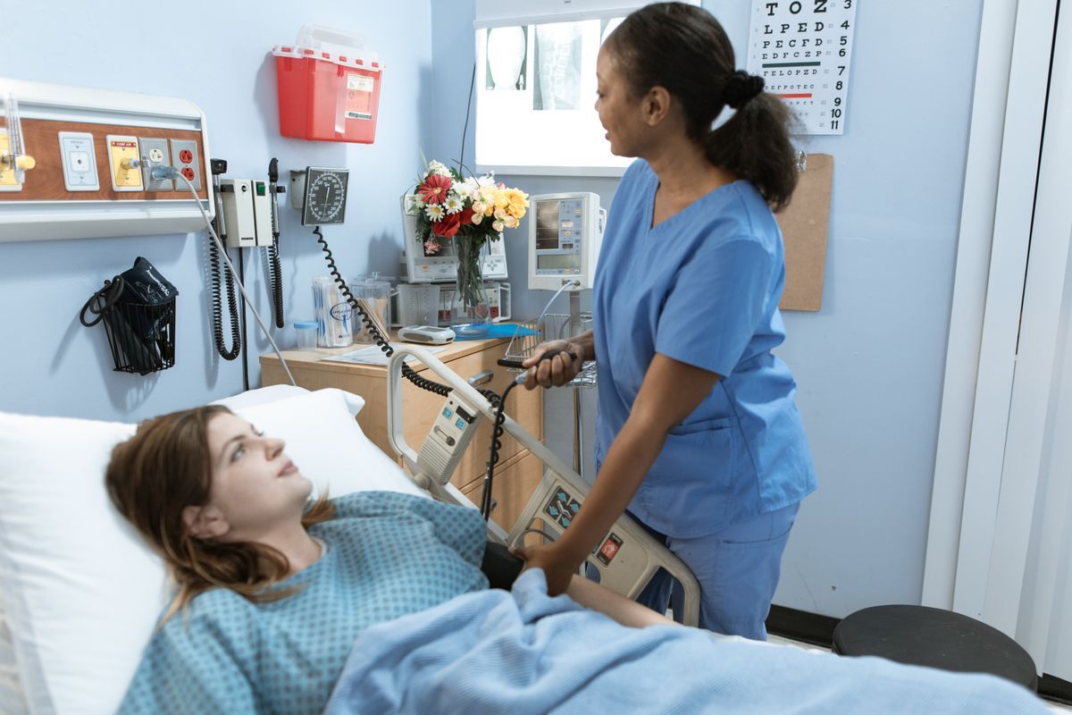 Pflegekraft misst den Blutdruck einer Patientin im Krankenbett